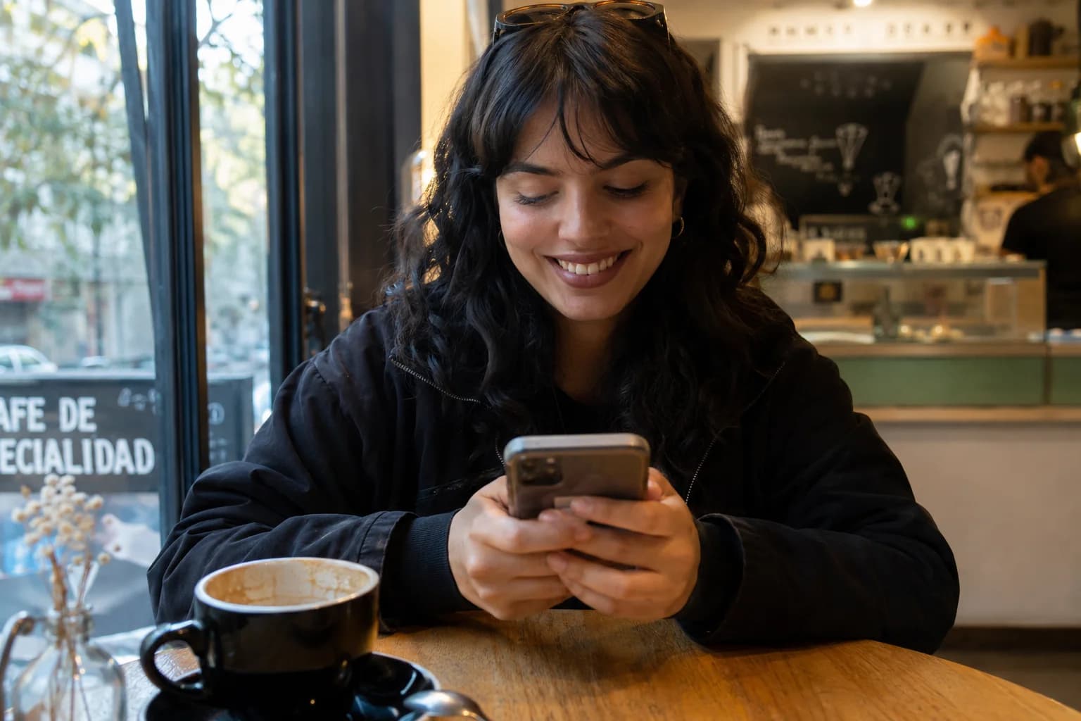 Persona en cafetería revisando una conversación en su teléfono